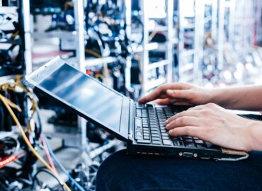 IT specialist working on computer in bitcoin and crypto currency mining farm.
