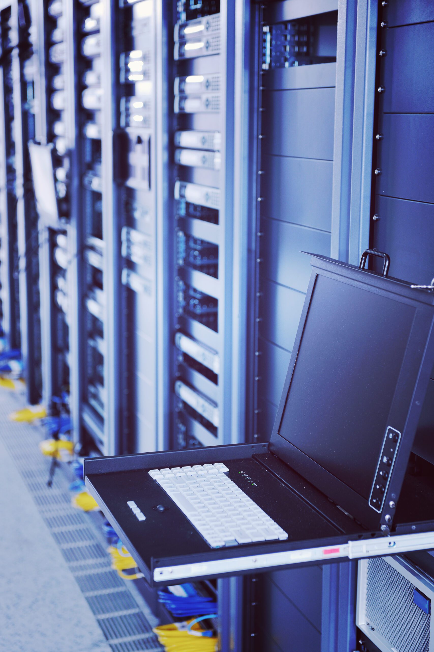 Network server room with server racks and a pull-out console featuring a keyboard and monitor, illustrating IT infrastructure and cybersecurity solutions.